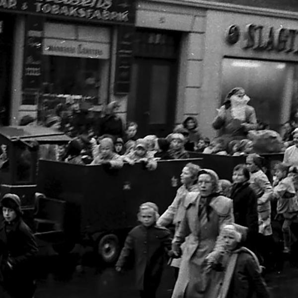 En stor bil med nisser kører forbi butikkerne i hovedgaden - i 1955