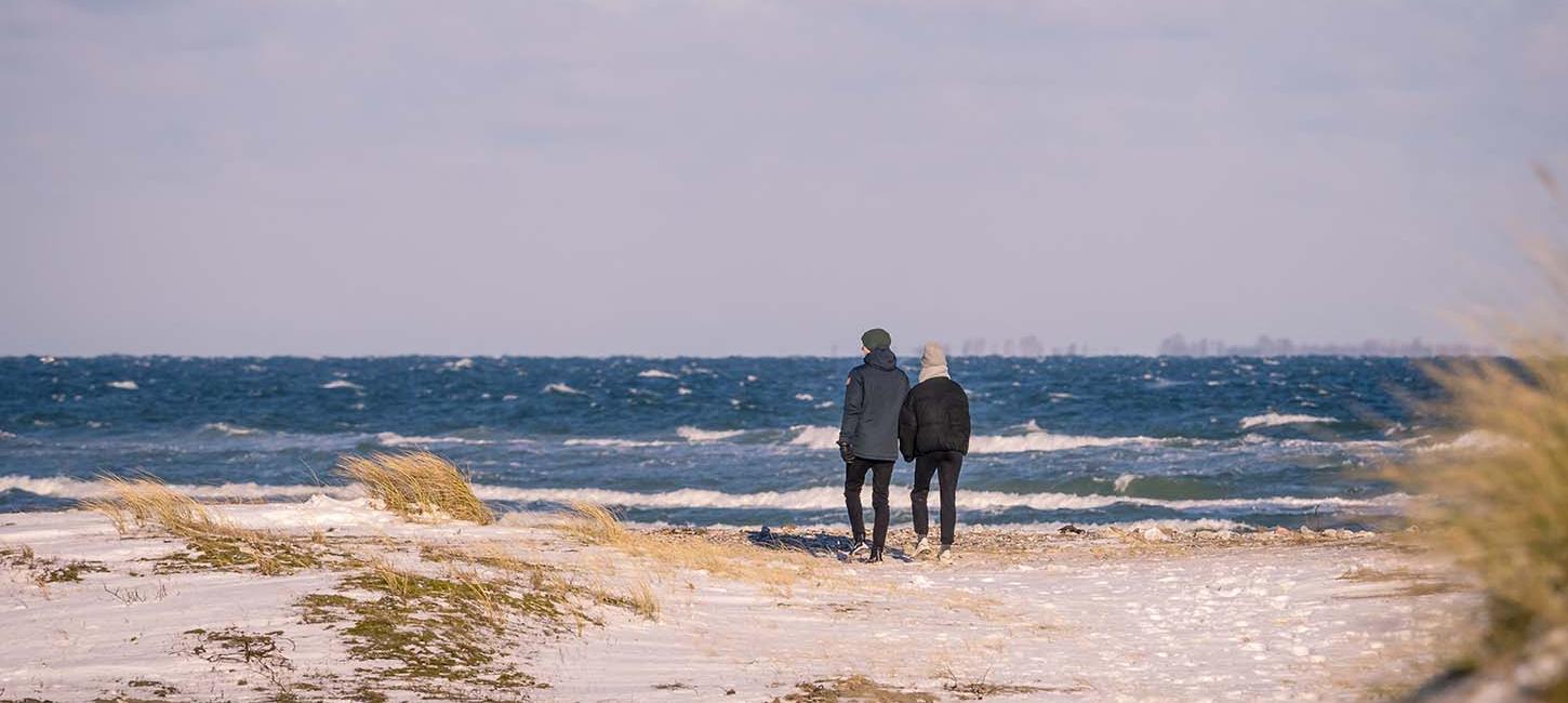Et par går på stranden på Flyvesandet i vintertid