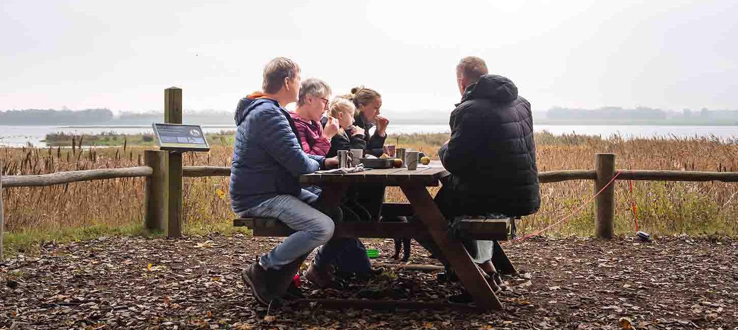 Familie holder picnic på Gyldensteen Strand i efteråret