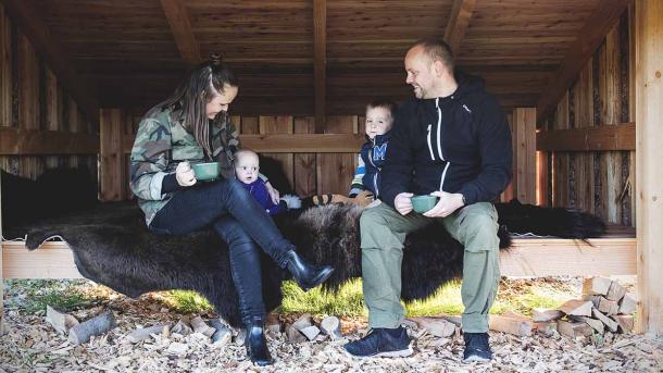 Mor, far og to små børn slapper af på et bisonskind i et stort shelter