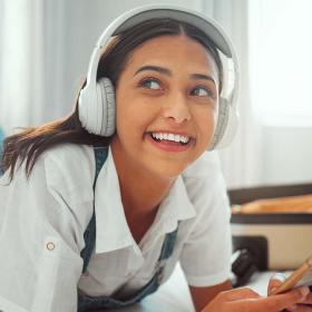 Glad kvinde lytter til musik på hotelseng