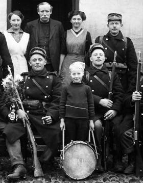 En gruppe soldater med geværer og en dreng med trommen