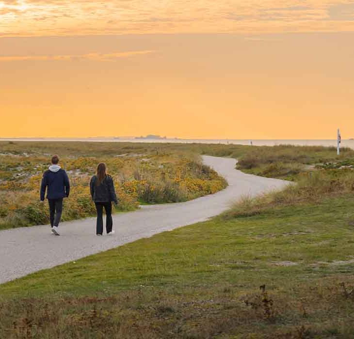 Par går tur ved Flyvesandet i solnedgang